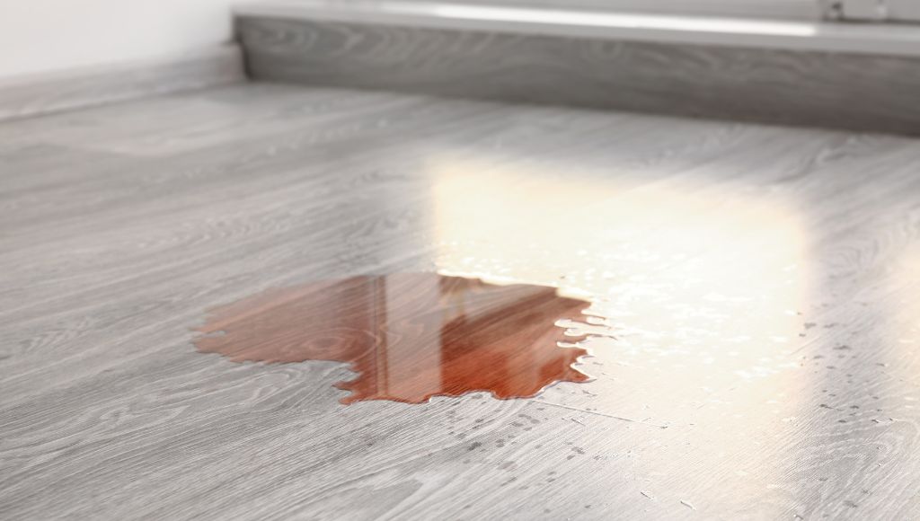 Close-up of a spill on waterproof laminate flooring, demonstrating its water resistance.