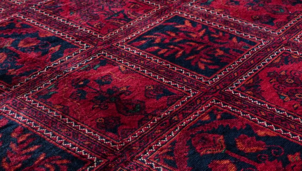 Close-up of a vibrant red and navy patterned carpet installed by Orange Cat Flooring, showcasing intricate designs and rich textures.