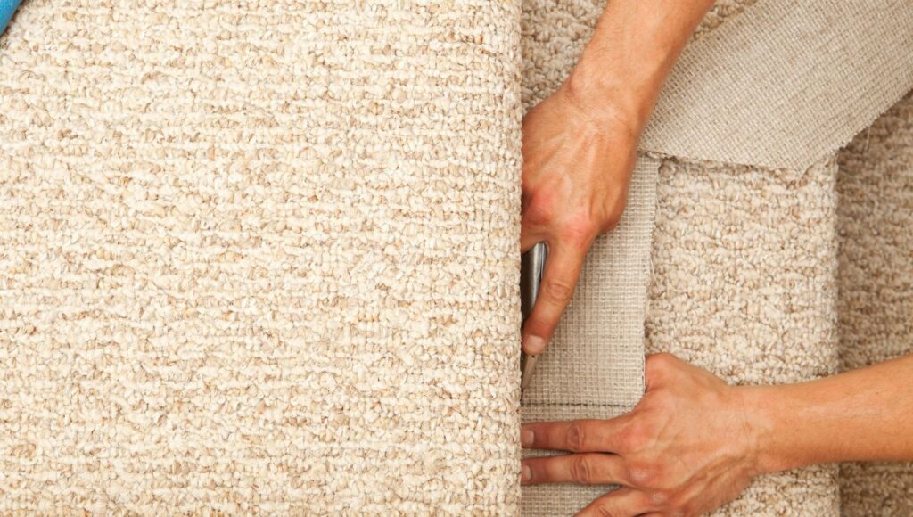 Close-up of professional carpet installation by Orange Cat Flooring, showing hands securing and aligning the carpet edges.