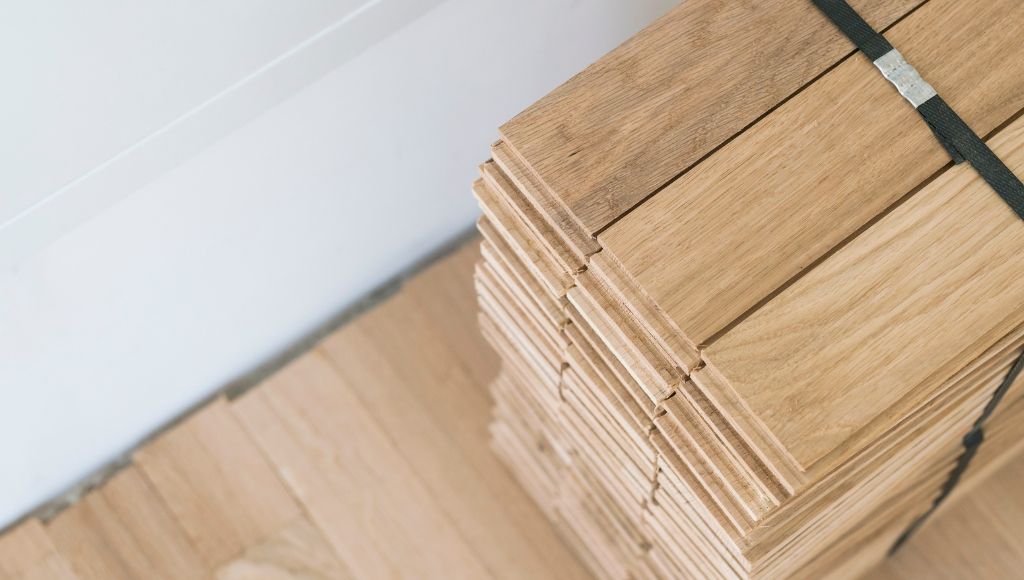 Stack of hardwood planks prepared for professional installation by Orange Cat Flooring.